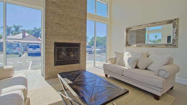 A spacious living room with a fireplace, large windows, a sofa, and a coffee table.