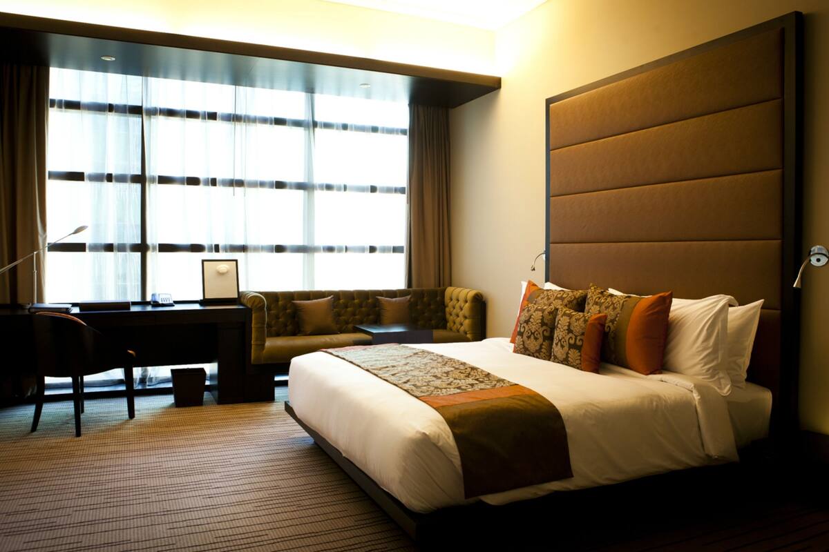 A hotel room with a large bed, a desk, and a sofa.