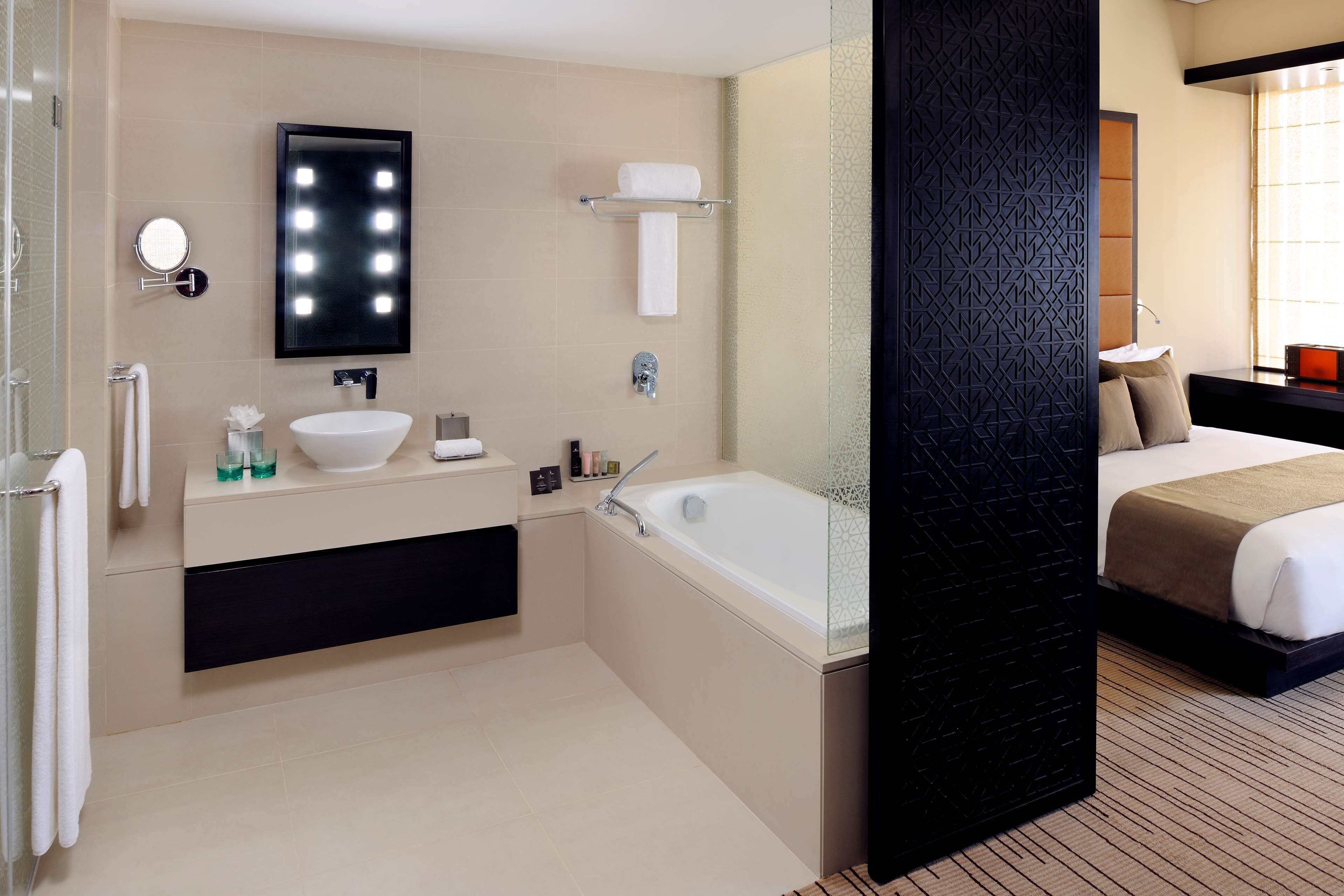 Un baño de hotel con lavamanos, espejo y bañera.