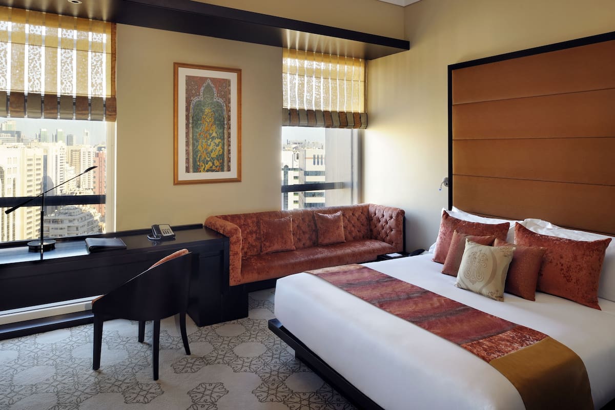 A hotel room with a bed, a sofa, a desk, and a chair.