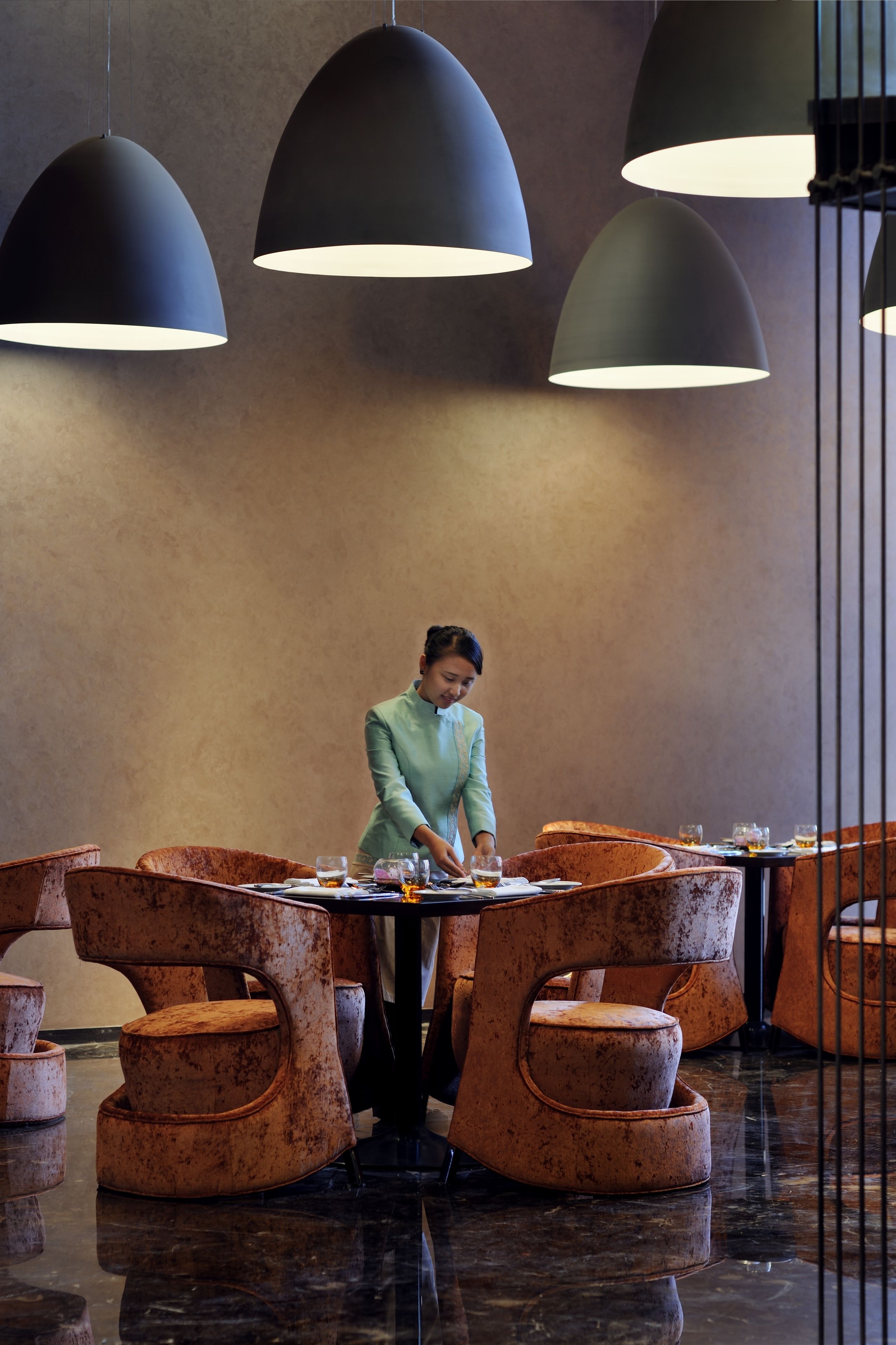 A restaurant with a modern interior, featuring unique orange chairs and large pendant lights.