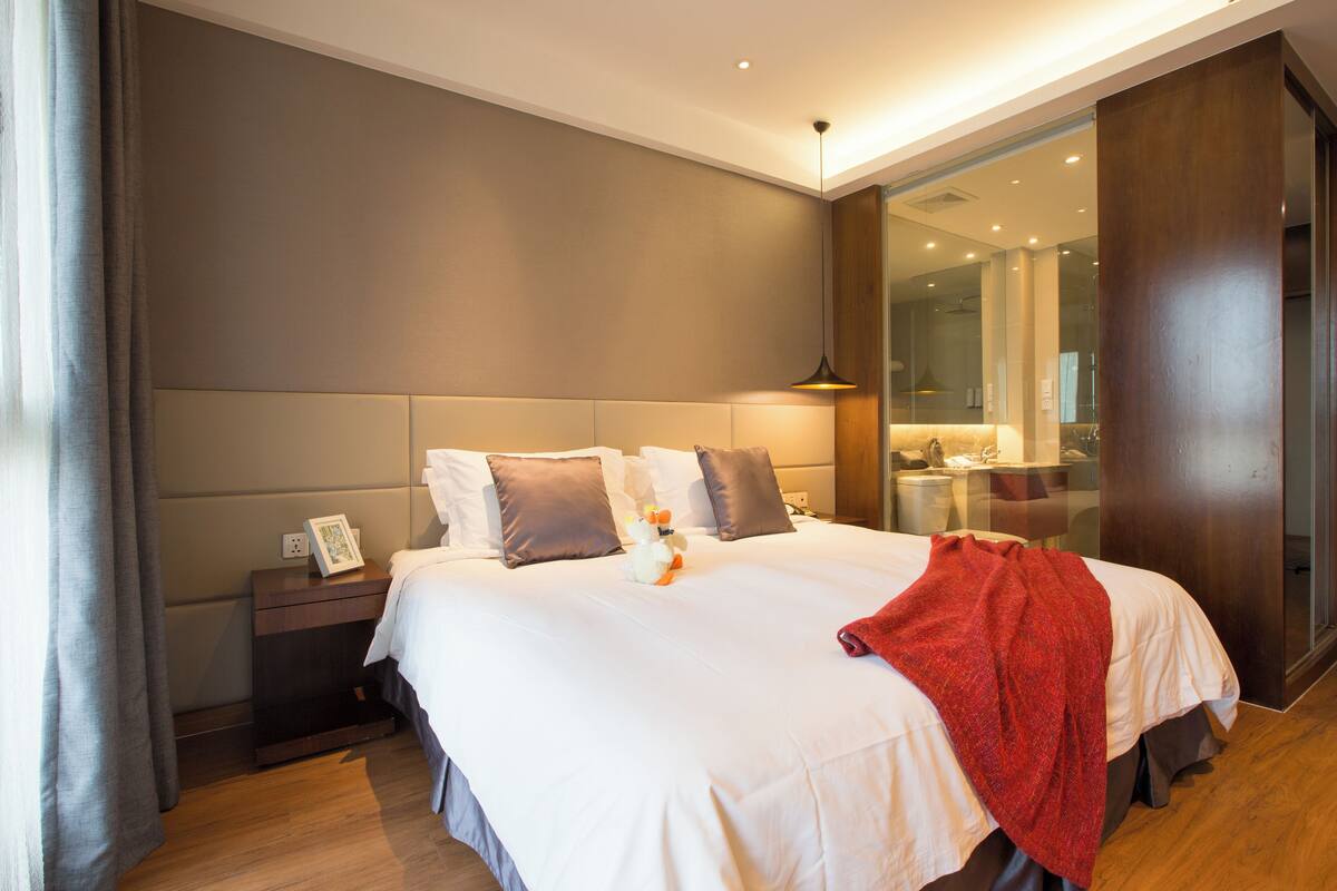 A modern hotel room with a large bed, a nightstand, and a mirror.