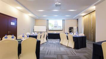 Un salón de conferencias con proyector, una pizarra y un amplio ventanal con vista a la ciudad.