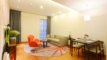 A modern living room with a sofa, orange armchairs, a coffee table, and a dining table set for four.