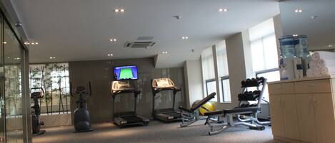 Un gimnasio con cintas de correr, una bicicleta estática y una máquina de remo.