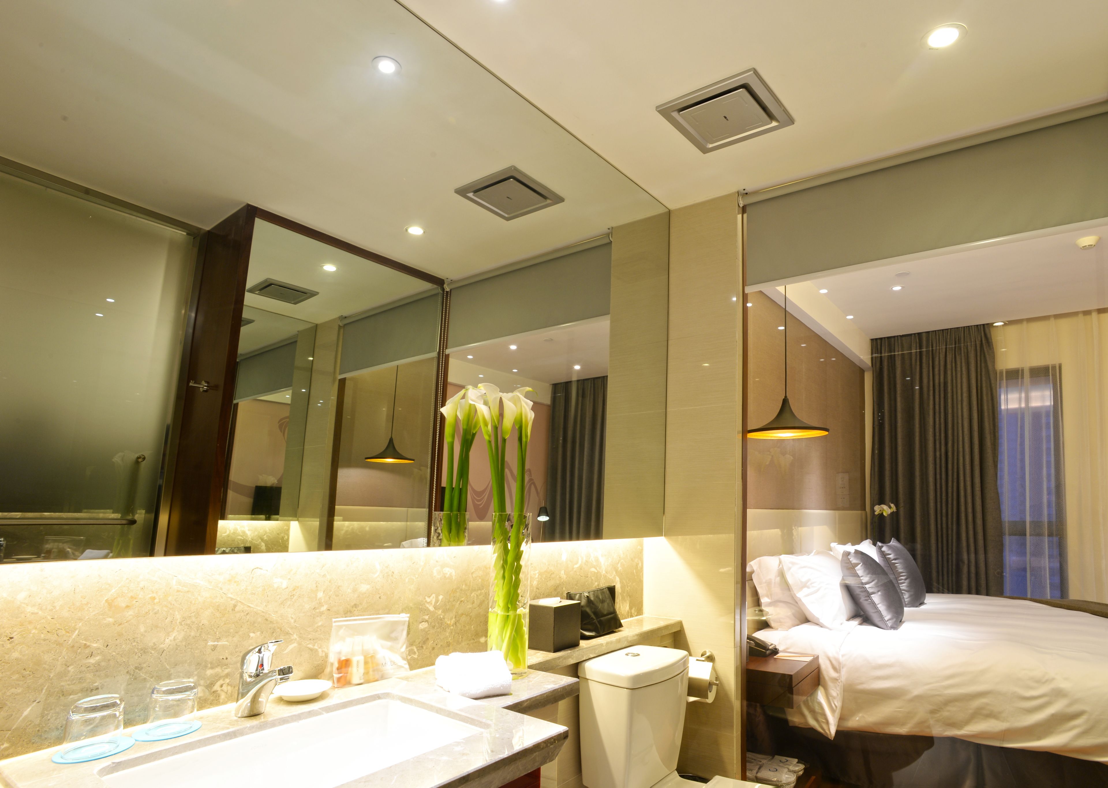 Un baño de hotel moderno con un espejo grande, un lavabo, un inodoro y una zona de ducha.