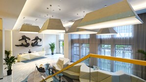 A modern lobby with a reception desk, seating area, and large windows. - Modena by Fraser New District Wuxi (Wuxi)