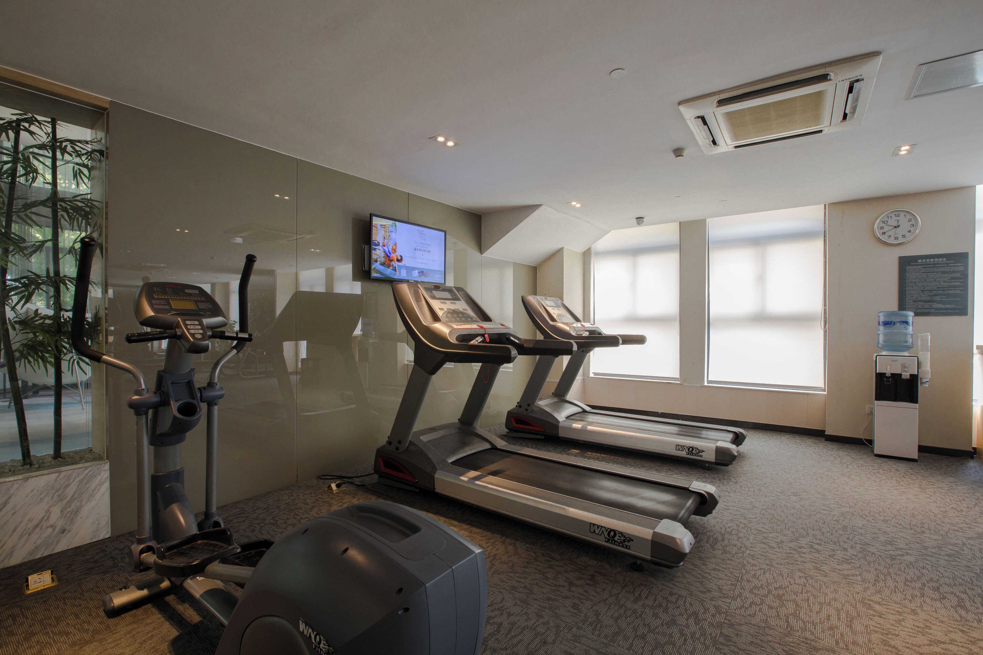 Et fitnessrum med løbebånd, crosstrainer og vægtbænk.