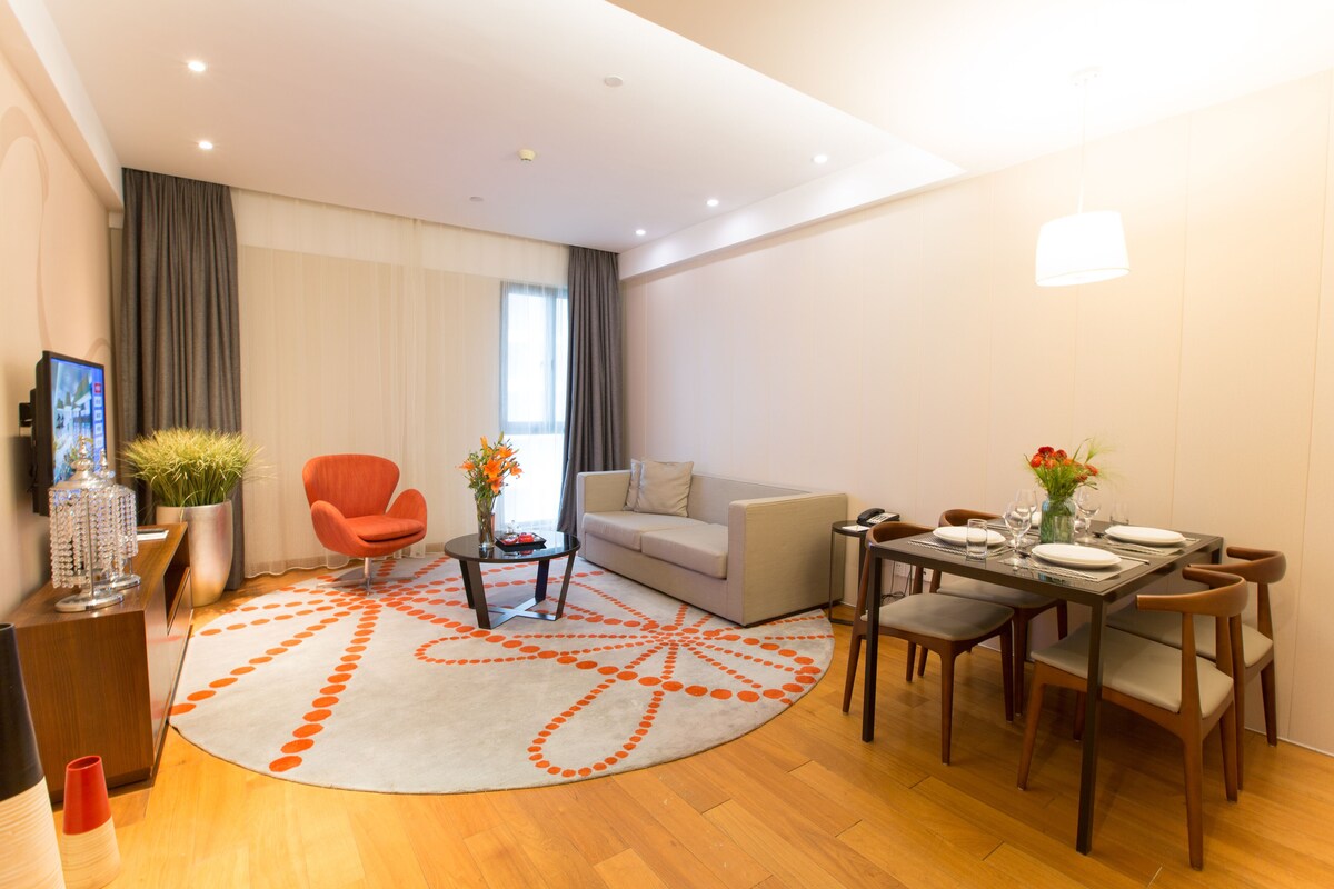 Una sala de estar moderna con comedor, un sofá, una mesa de centro y un televisor.