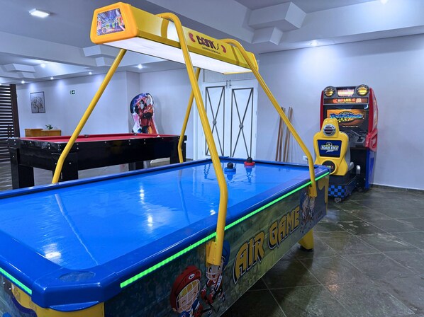 A pool table with a yellow overhead rail and a pool cue.