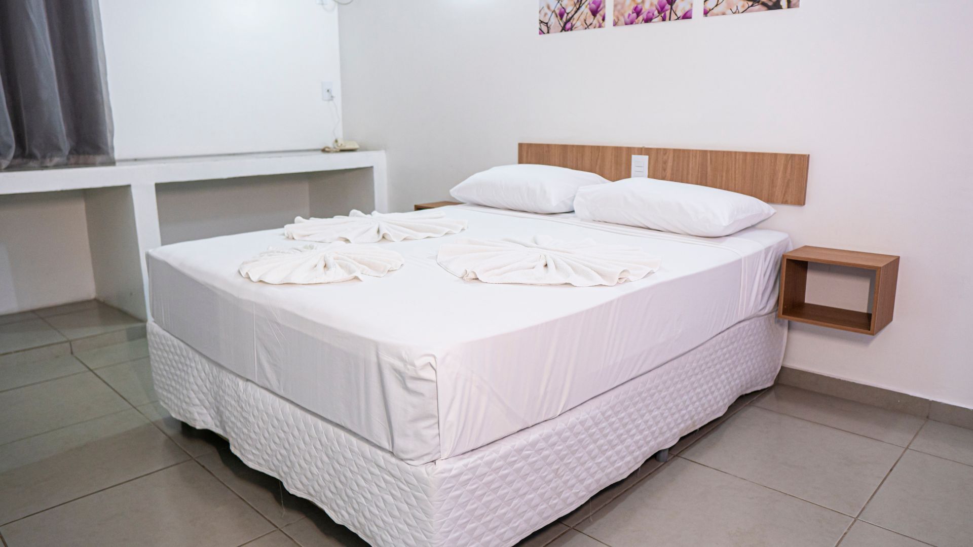 A neatly made bed with white linens and towels arranged on the bed.