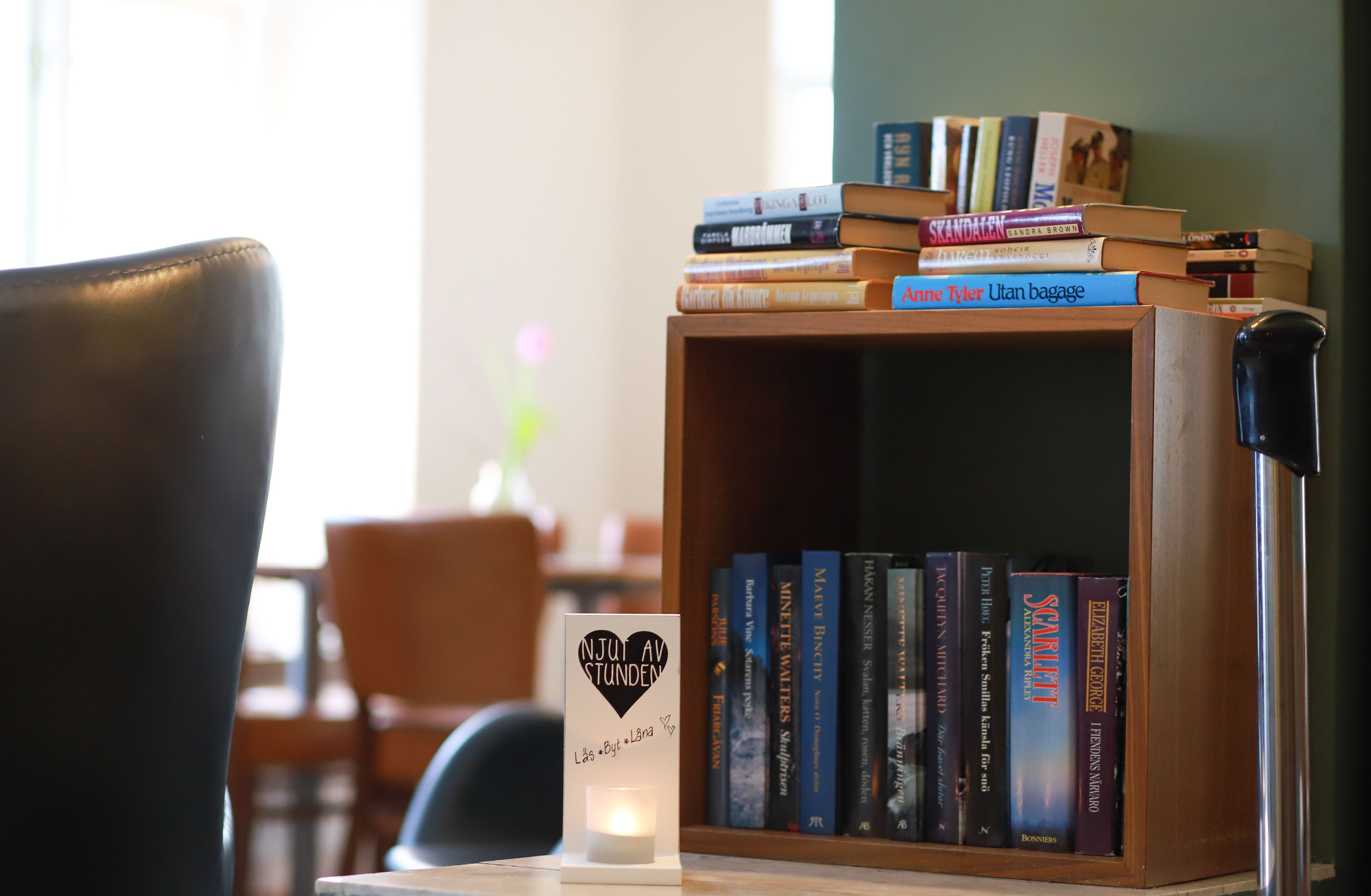 Una estantería de madera con libros, una vela y una silla.