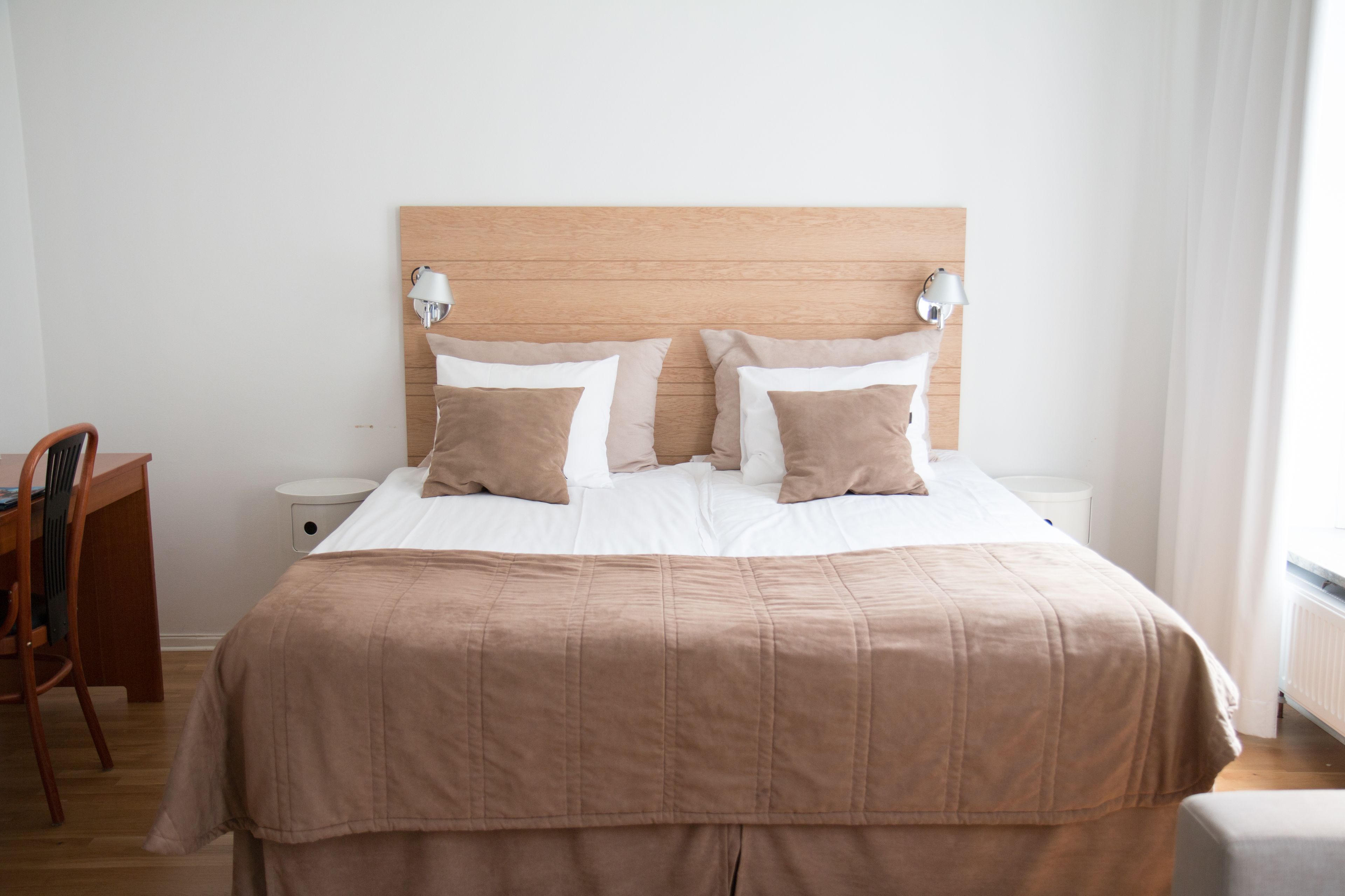 A neatly made bed with a wooden headboard, two bedside lamps, and a wooden nightstand.