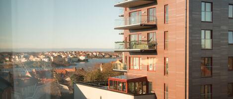 A modern building with multiple balconies and a view of a river and town.