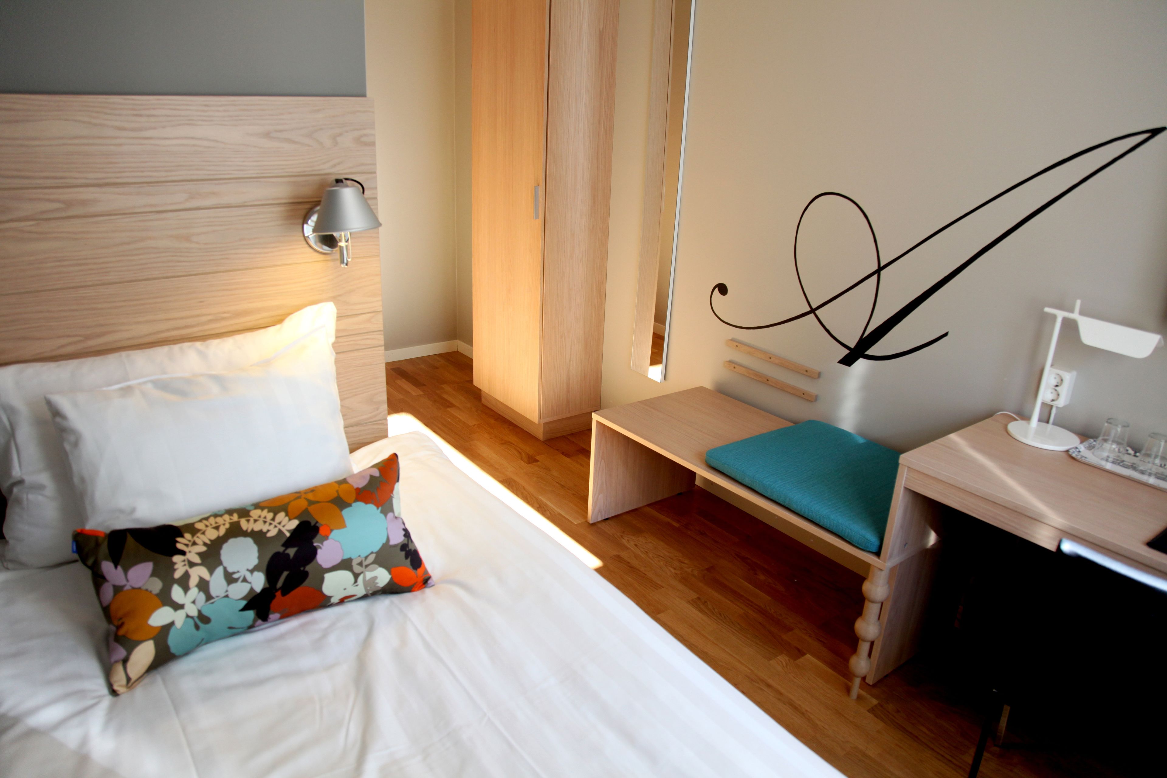 A hotel room with a bed, a desk, a chair, and a nightstand.