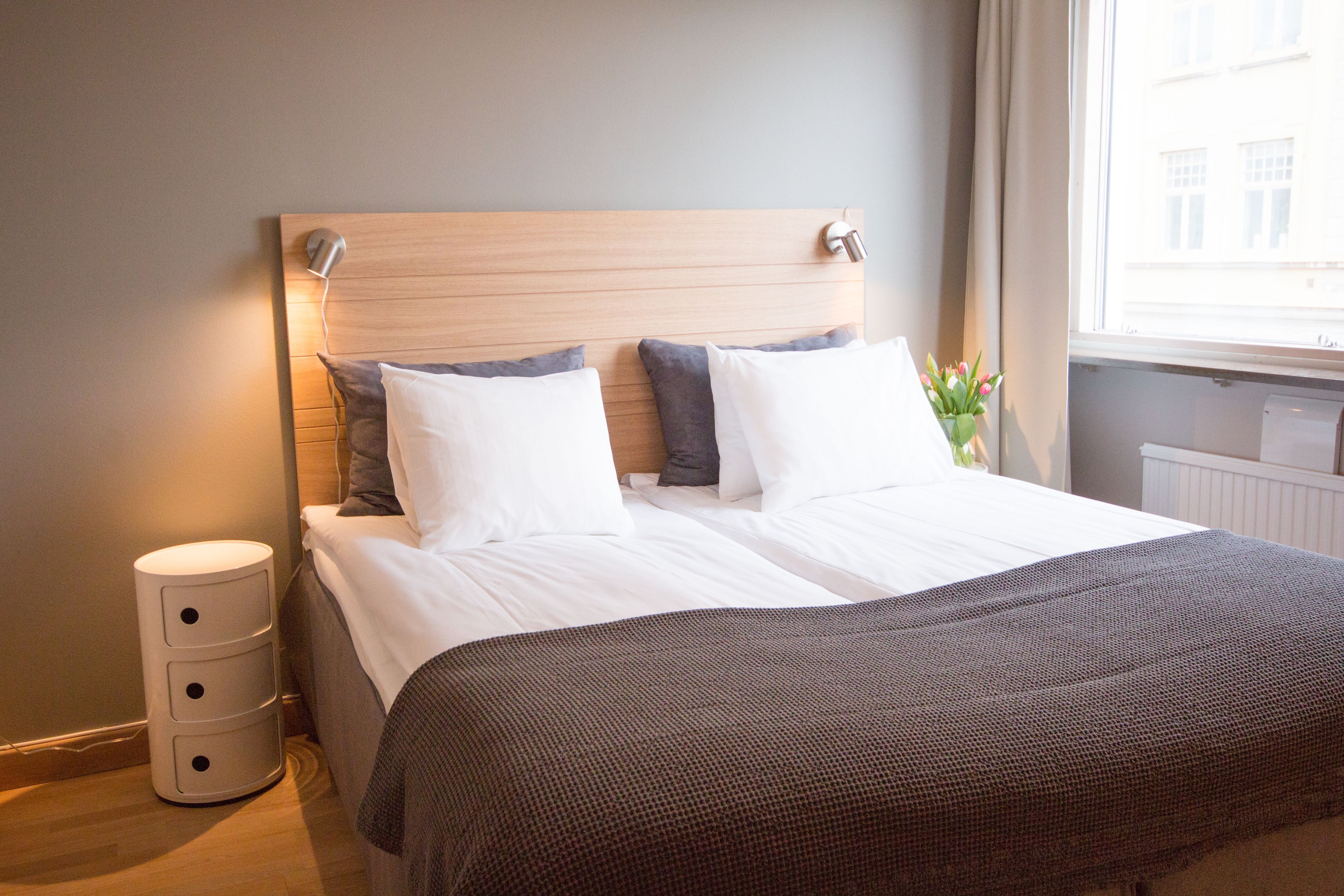 A neatly made bed with a wooden headboard, a bedside lamp, and a small bedside table.