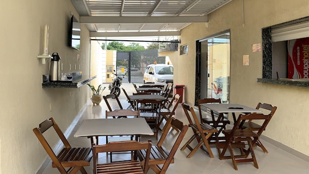 Un restaurante con varias mesas y sillas, una barra y vista a la calle.