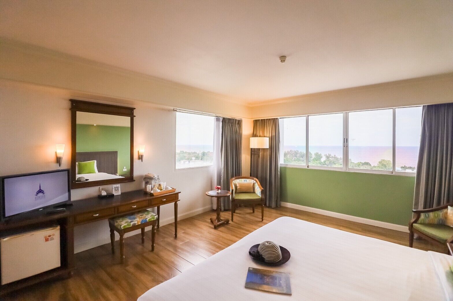 Habitación de hotel con cama, escritorio, silla, televisor y vista al mar.