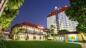 A hotel with a well-maintained lawn, a prominent sign, and a large building in the background. - HUA HIN GRAND HOTEL AND PLAZA (Hua Hin)