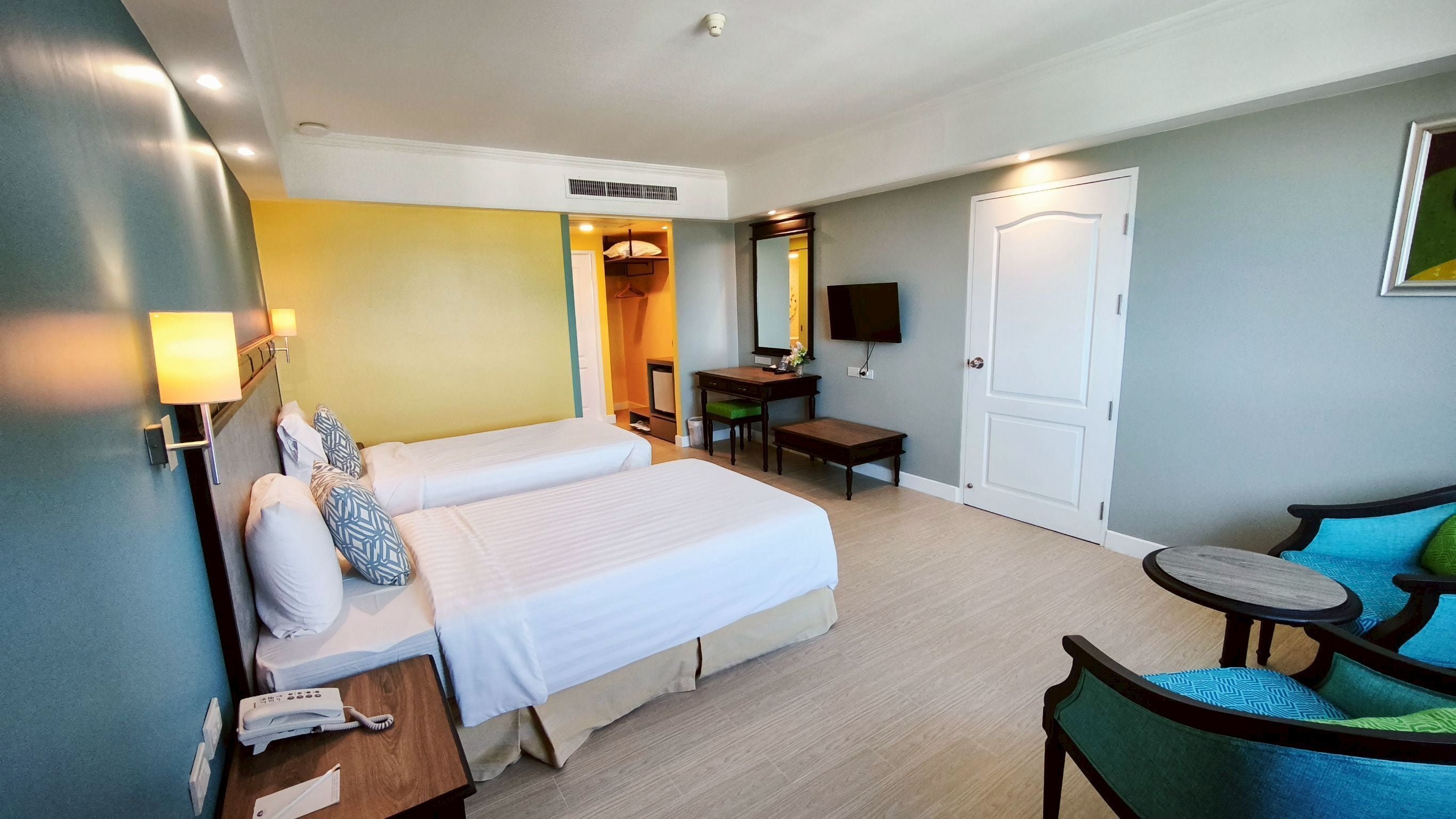 Ein Hotelzimmer mit zwei Betten, einem Schreibtisch, einem Stuhl, einem Fernseher und einer Tür.