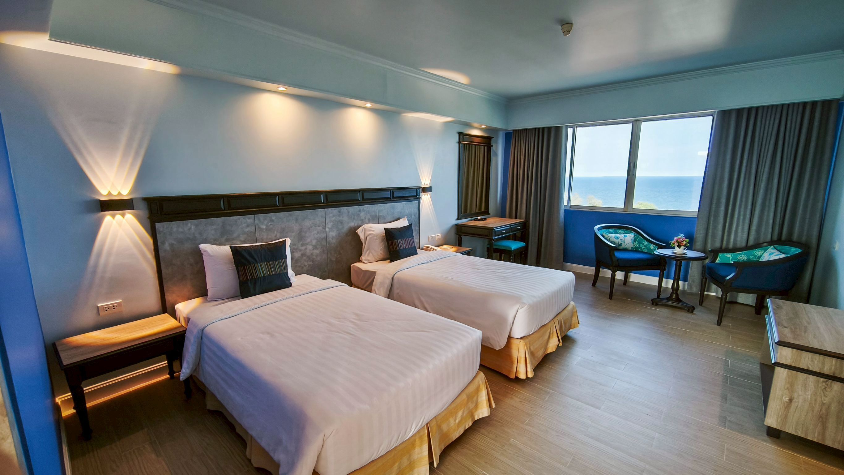 Une chambre d’hôtel avec deux lits, un bureau, une chaise et une vue sur la mer.