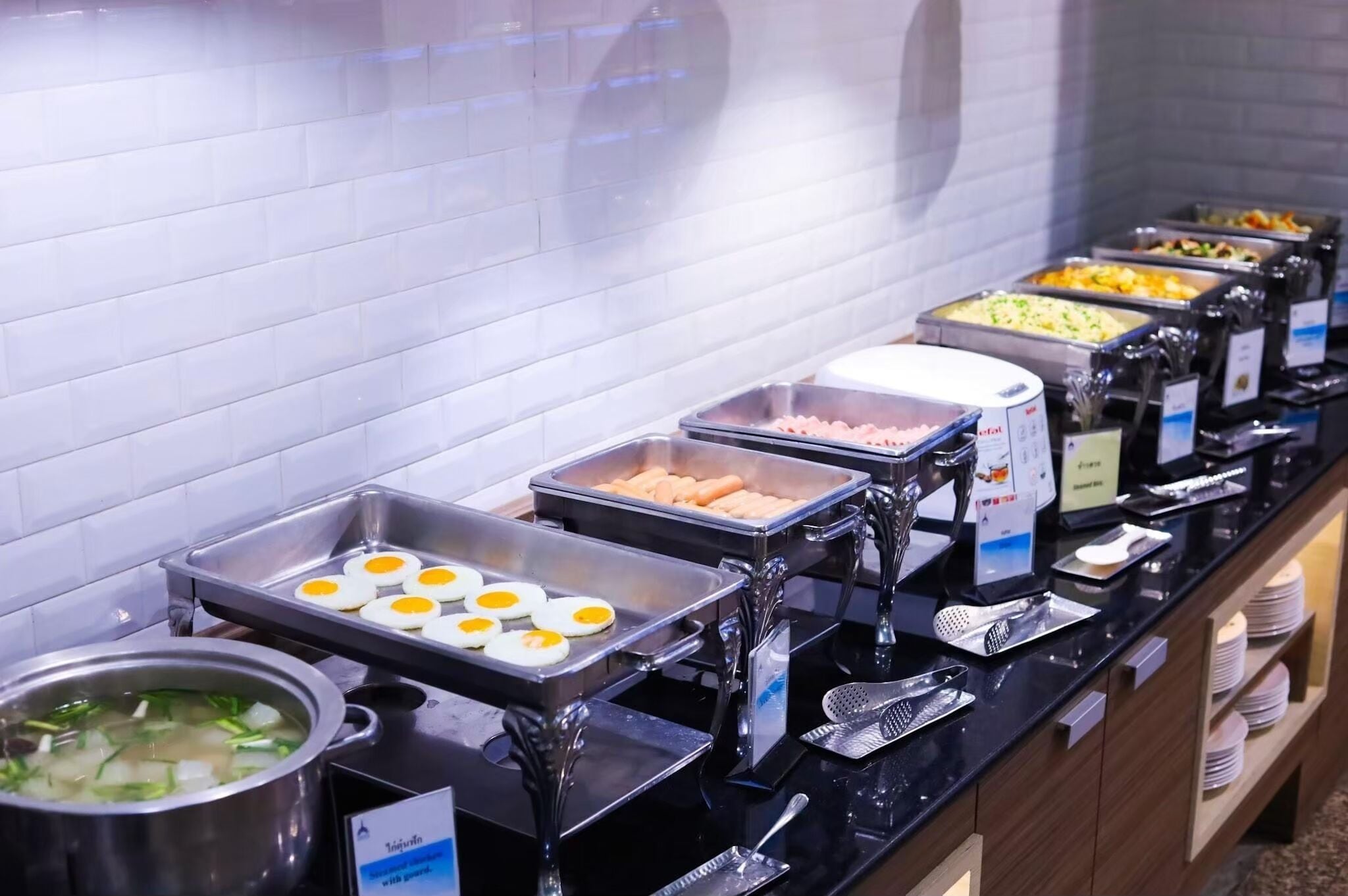 A buffet with various food options, including eggs, meats, and soups.