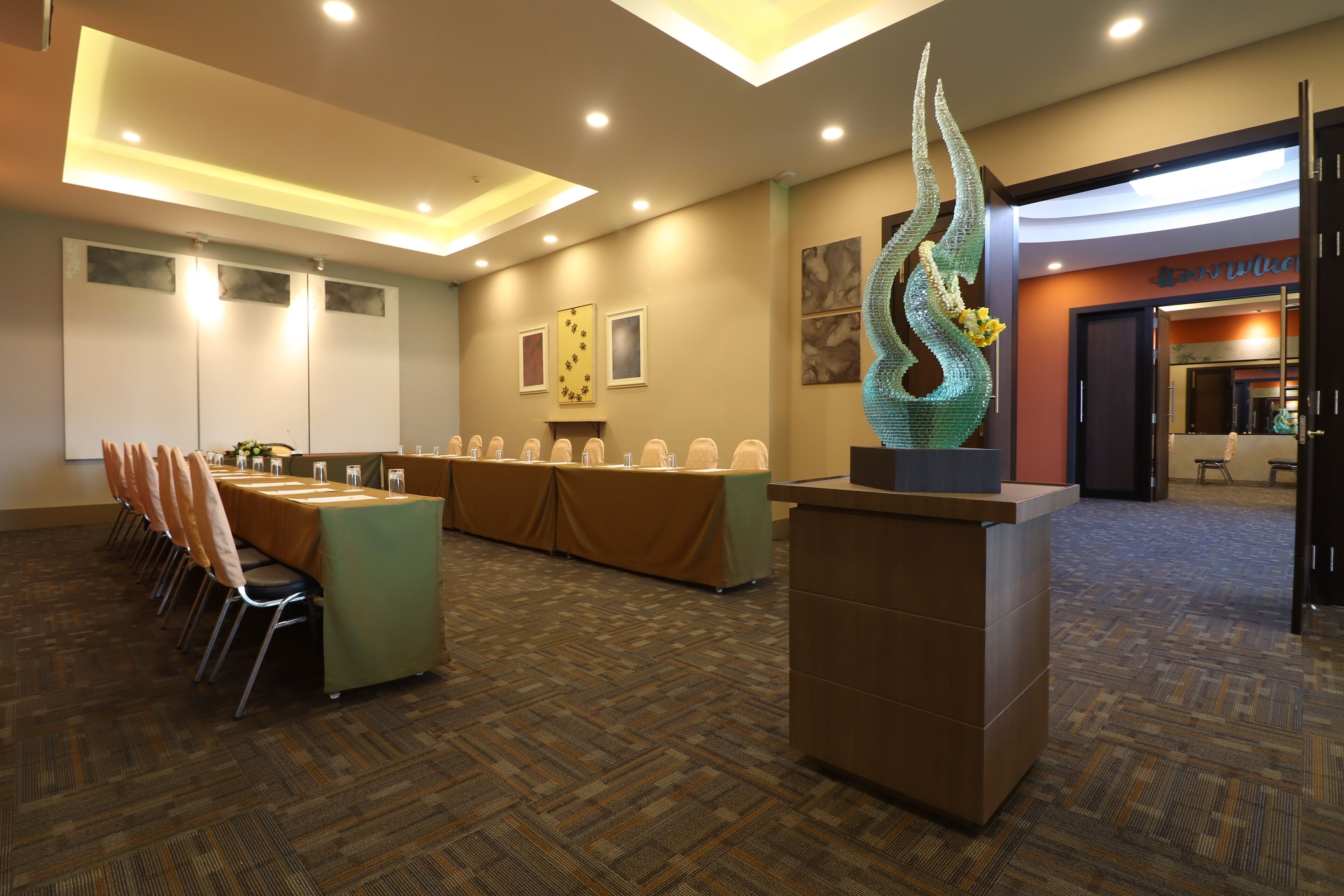A conference room with a long table, chairs, a reception desk, and a decorative sculpture.