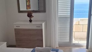 Habitación de hotel con cama, cómoda, espejo y vista al océano.