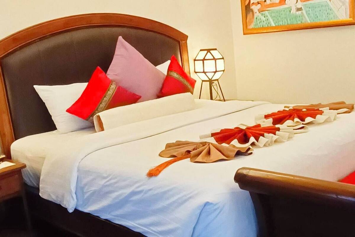 A neatly made bed with white bedding and red and white decorative ribbons.