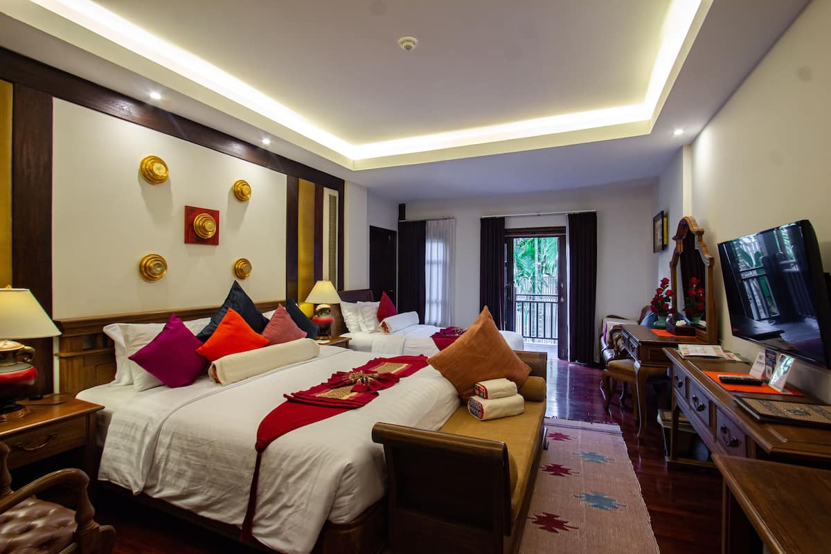 A hotel room with two beds, a desk, a TV, and a balcony with a view.