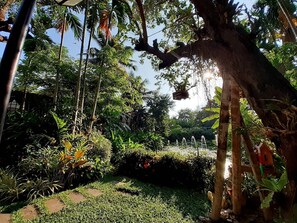 A lush garden with a variety of plants and trees, a small water feature, and a clear sky. - Viang Thapae Resort (Chiang Mai)