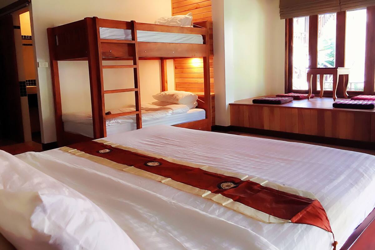 Ein Zimmer mit einem Etagenbett, einem Einzelbett und einer Bank mit Kissen.