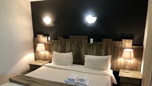 A hotel room with a large bed, two bedside lamps, a wooden headboard, and a nightstand with a lamp. - Valverde Country Hotel (Muldersdrift)