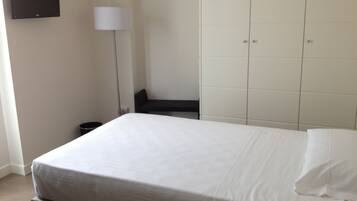 Une chambre d’hôtel avec un lit, une table de chevet, une lampe et une armoire.