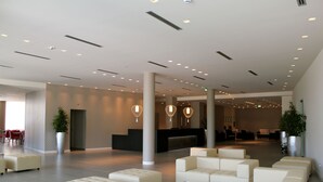Un amplio vestíbulo con mostrador de recepción, zonas de estar e iluminación moderna.