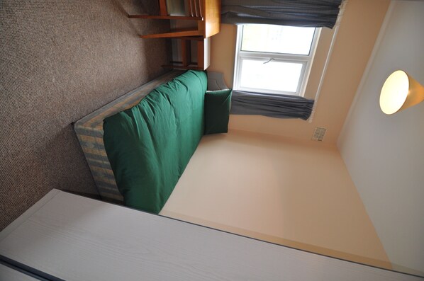 A compact room with a bunk bed, a small table, and a window with curtains. - The Stables (Galway)