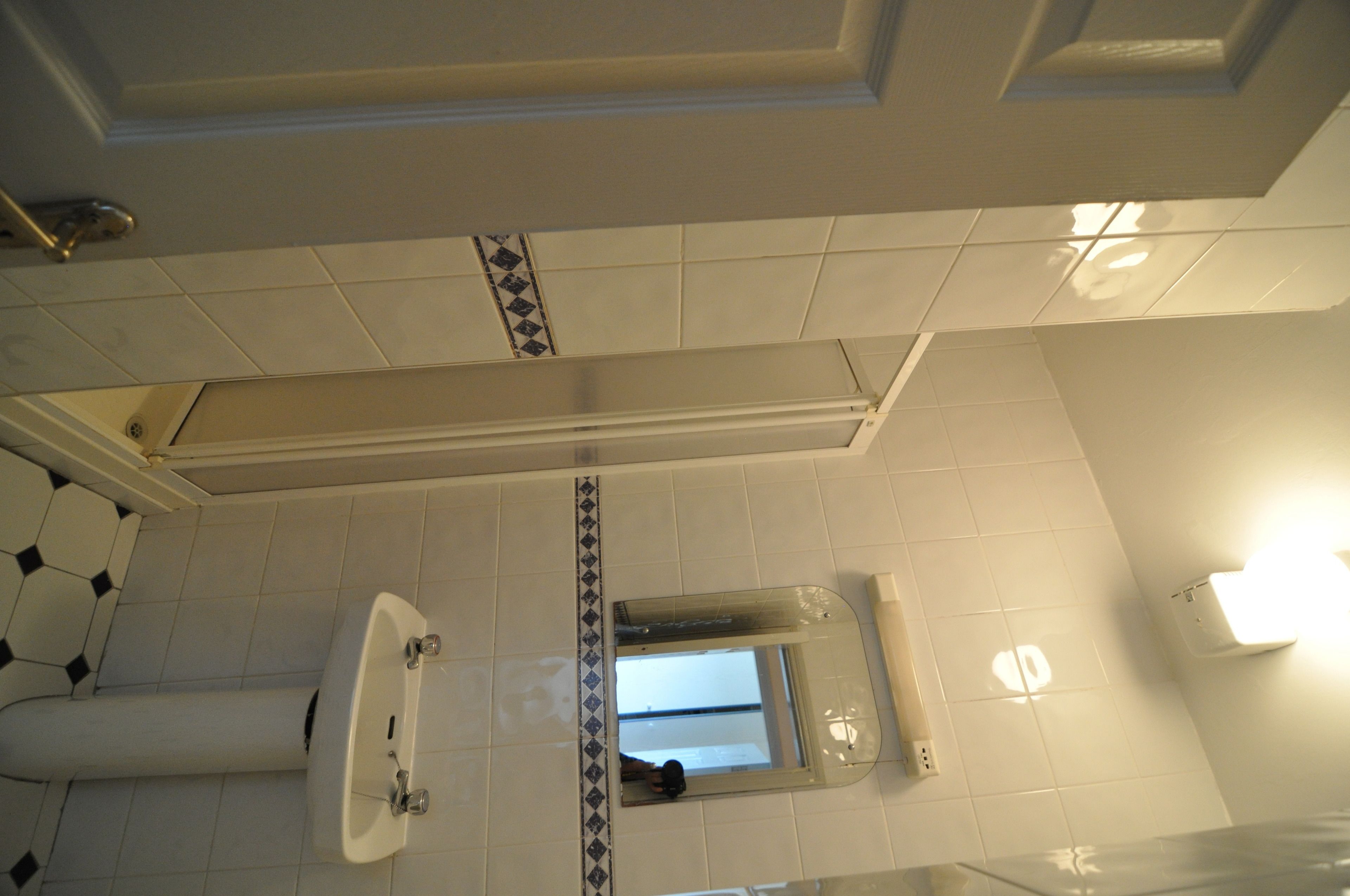 Une salle de bain avec un lavabo, un miroir et un sol carrelé.