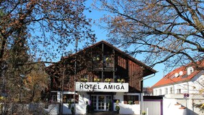 Un hotel llamado "HOTEL AMIGA" con un estilo arquitectónico tradicional, que presenta una fachada de madera y un letrero.