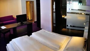 Habitación de hotel con cama, escritorio, silla y sofá púrpura.