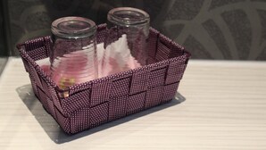 Una cesta morada con dos frascos de vidrio que contienen elementos rosados y blancos.