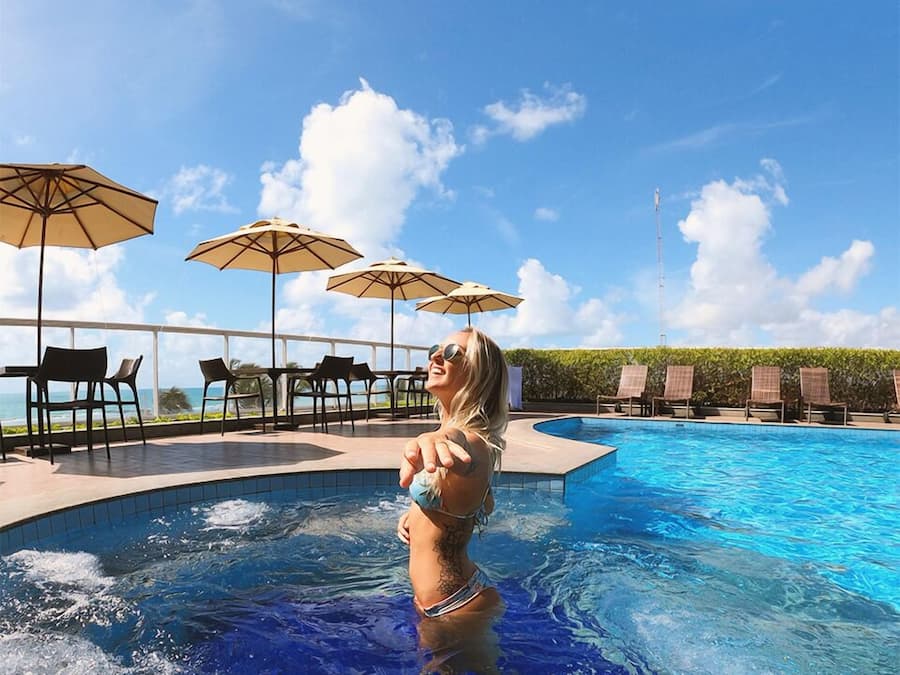 Una piscina al aire libre, sombrillas, sillones reclinables de piscina