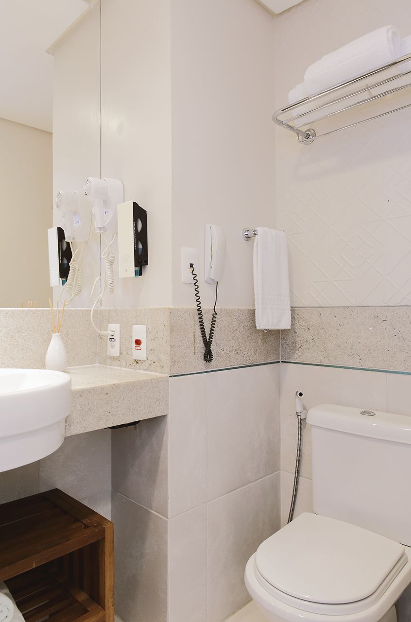 A bathroom with a white sink, a mirror, a towel rack, a toilet, and a shower.