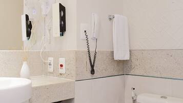 A bathroom with a white sink, a mirror, a towel rack, a toilet, and a shower.