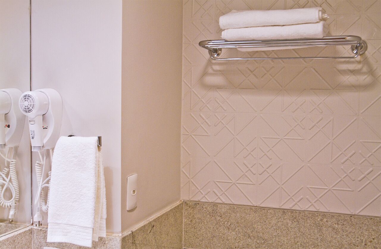 A bathroom with a towel rack, a hairdryer, and a towel hanging on the wall.