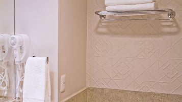A bathroom with a towel rack, a hairdryer, and a towel hanging on the wall.