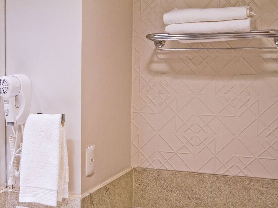 A bathroom with a towel rack, a hairdryer, and a towel hanging on the wall.
