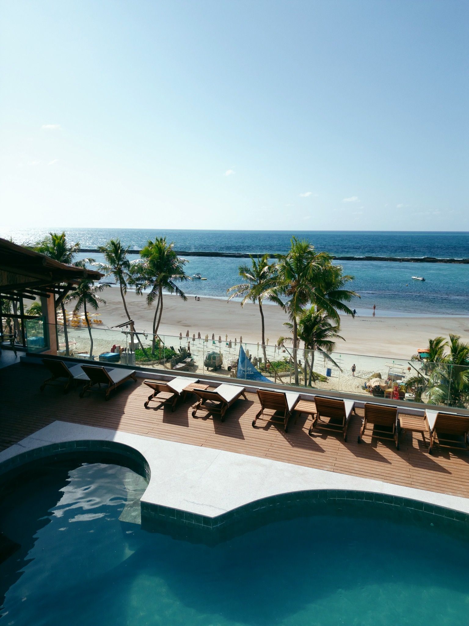 Zona de piscina con sillones de descanso y vista a la playa.