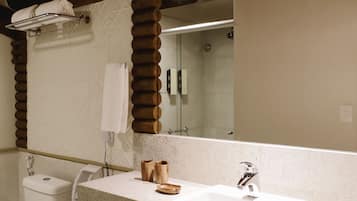 A modern bathroom with a wooden ceiling, a large mirror, a sink, and a toilet.