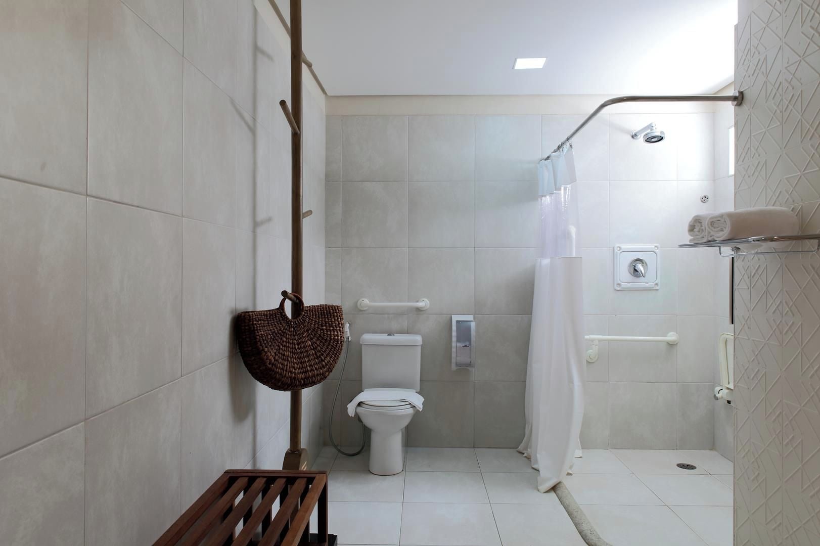 Ein Badezimmer mit Dusche, Toilette und Sitzbank.