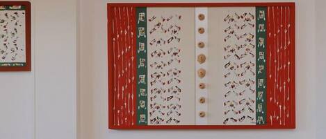 A room with a large wall-mounted artwork featuring a red and green color scheme with patterns and text.